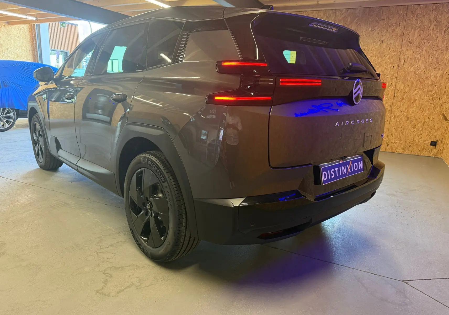 Vue 3/4 arrière droite du Citroën C5 Aircross gris hybride 2026 avec feux LED allumés en intérieur.