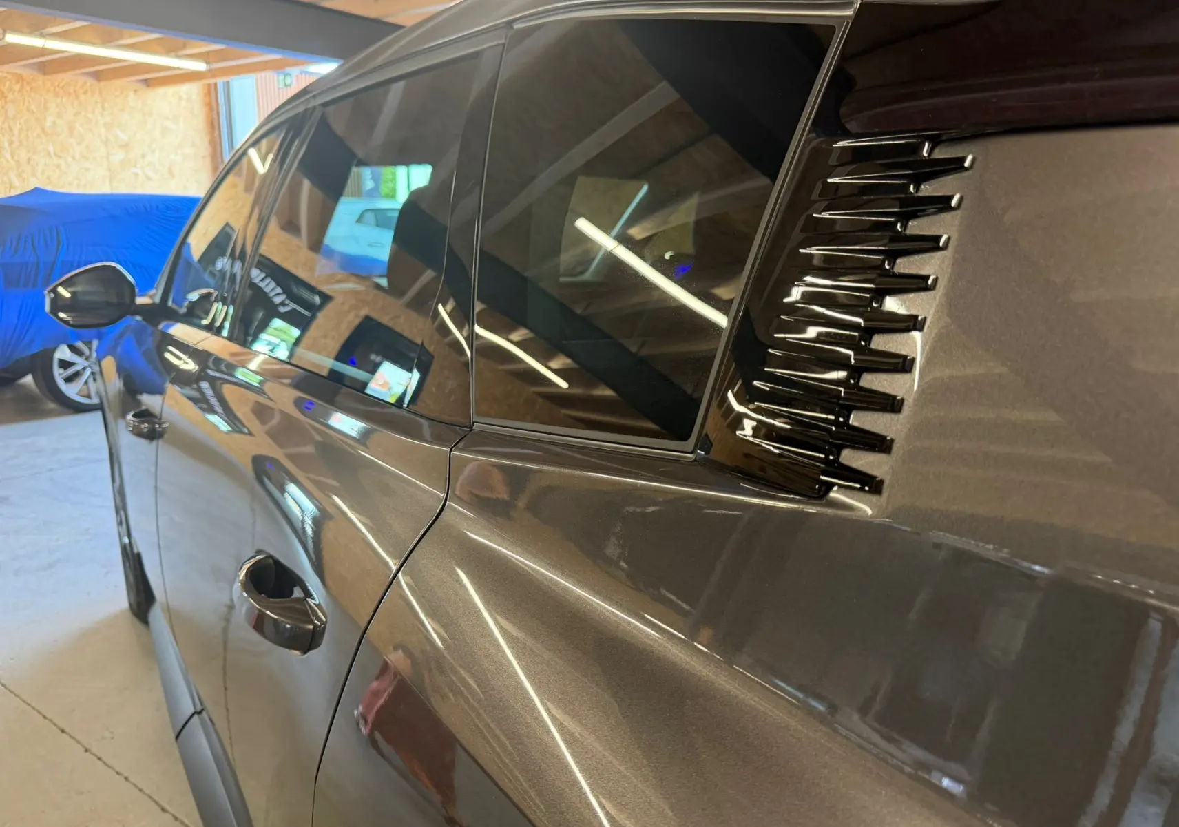 Vue latérale gauche rapprochée d’un Citroën C5 Aircross gris 2026, mettant en valeur les vitres teintées et les détails noirs décoratifs arrière.
