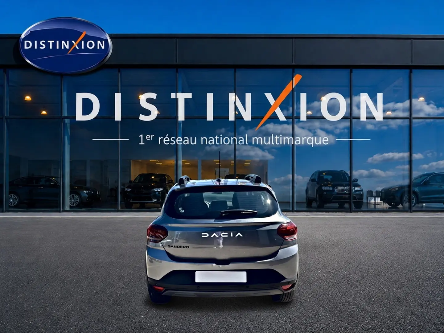 Vue arrière d'une Dacia Sandero gris schiste garée devant une vitrine avec logo Distinxion.