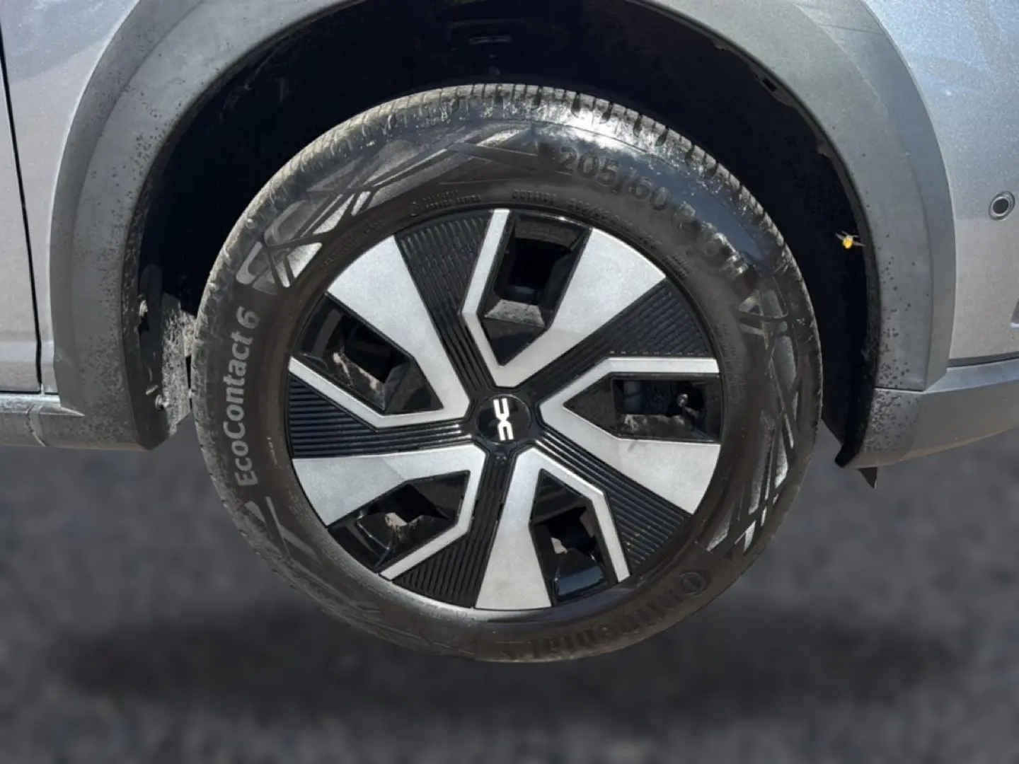 Gros plan sur la roue avant droite du Dacia Sandero gris schiste, avec jante au design moderne bicolore.