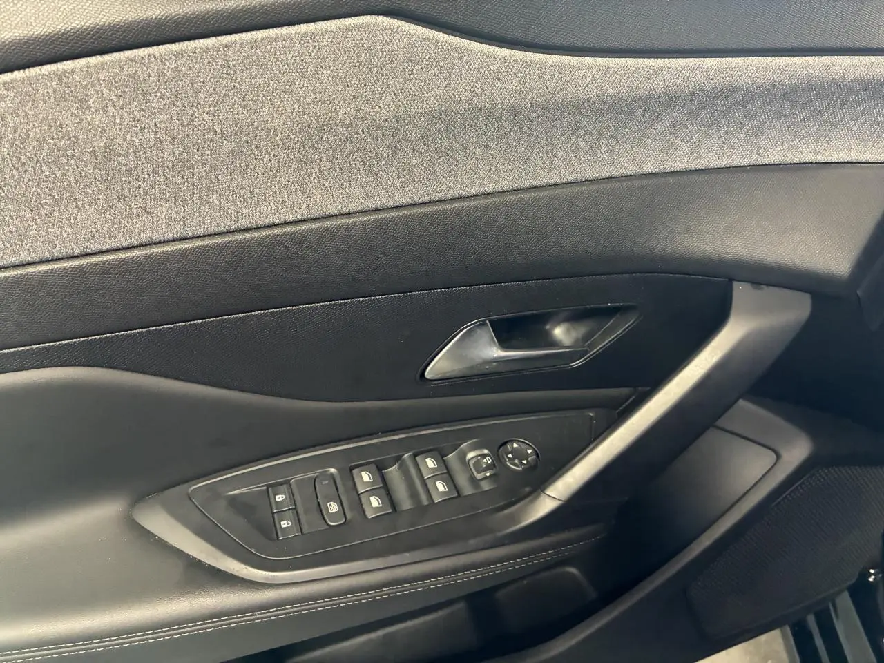 Gros plan sur la porte côté gauche de la Peugeot 308 SW noire, avec commandes des vitres et poignée intégrée.