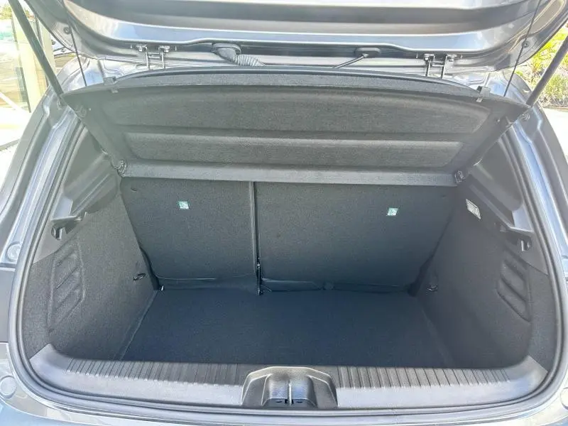 Coffre ouvert vu de l'arrière d'une Renault Clio 2025 gris Rafale, montrant l'espace de chargement et la banquette arrière rabattable.