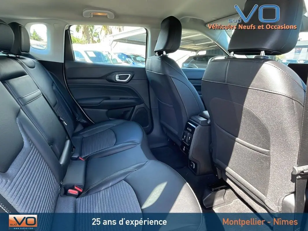 Vue intérieure arrière du Jeep Compass 2024 blanc, sièges en cuir noir avec accoudoir central et ventilation arrière.