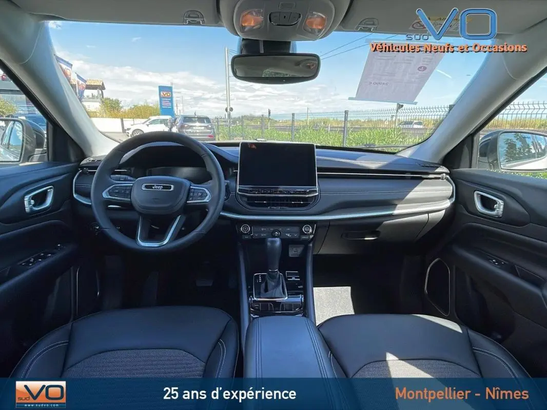 Vue intérieure avant du Jeep Compass 2024 avec tableau de bord moderne, écran tactile et volant multifonction noir.