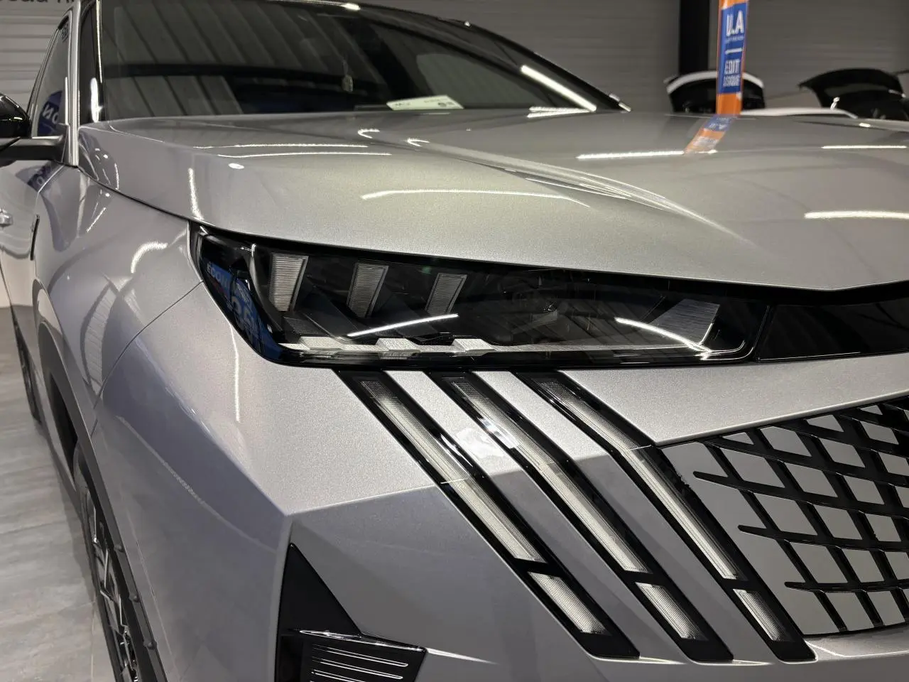 Gros plan sur l’avant droit du Peugeot 3008 gris Artense, mettant en valeur les phares LED et la calandre noire.