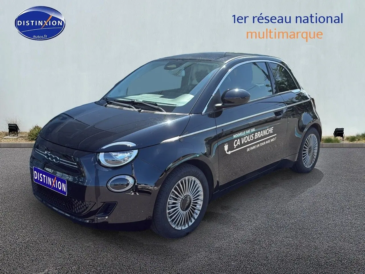 Vue 3/4 avant droite d'une Fiat 500 électrique noire avec lettrage publicitaire sur la porte côté droit.