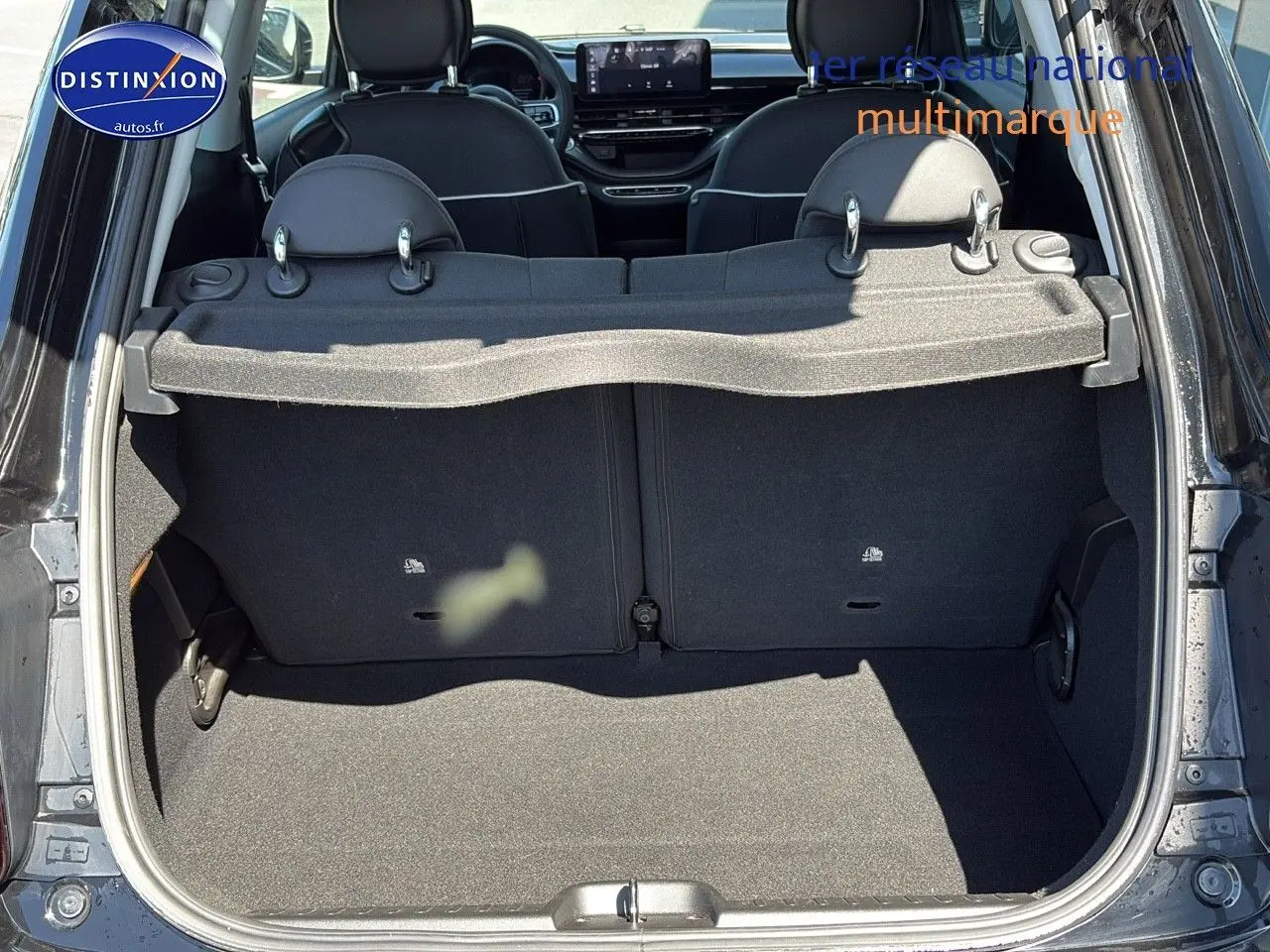 Coffre ouvert vu de l'arrière d'une Fiat 500 électrique blanche 2024 avec banquette arrière et tablette cache-bagages.