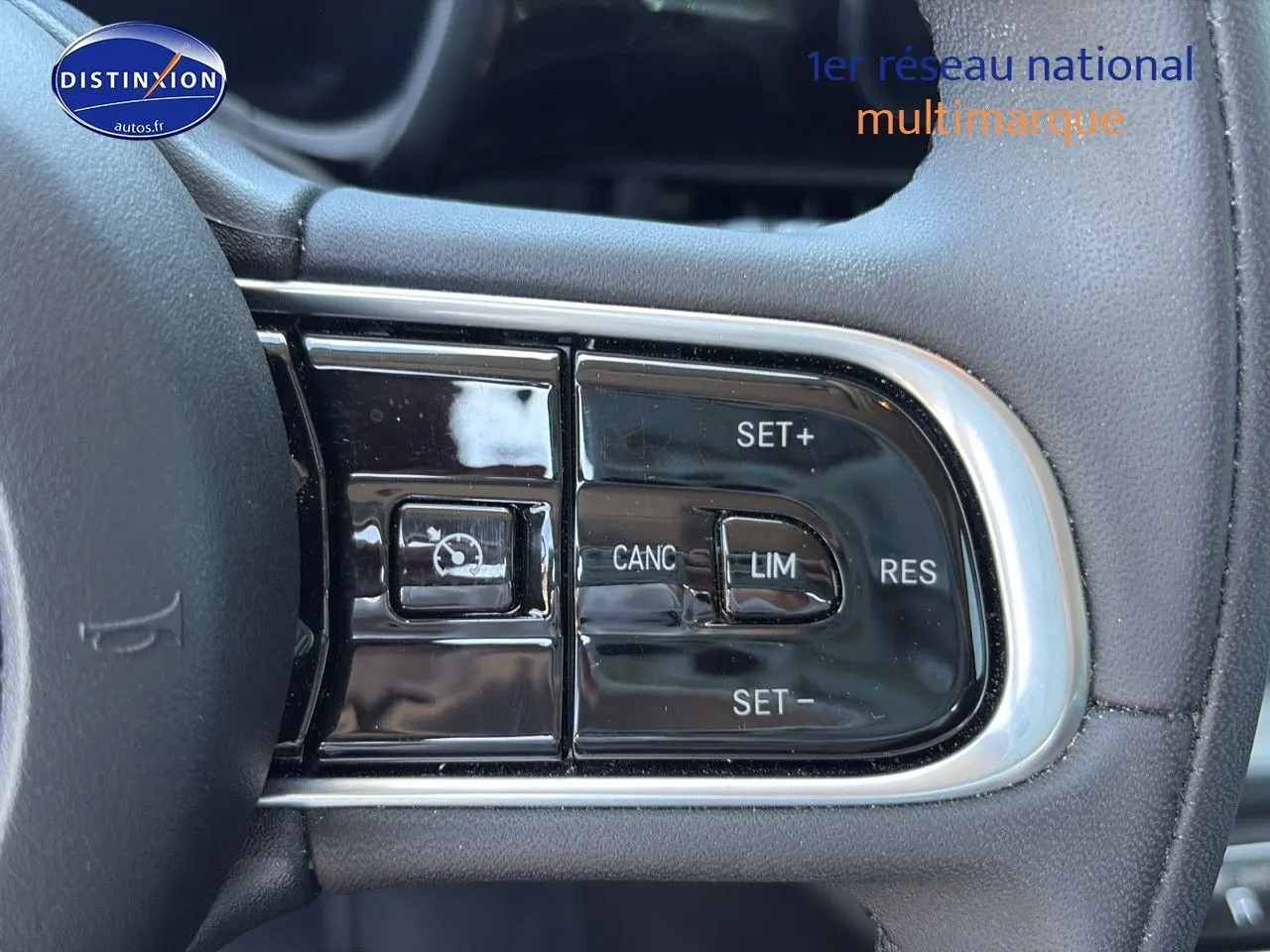 Gros plan sur les commandes du régulateur de vitesse au volant noir de la Fiat 500 électrique blanche MY23.