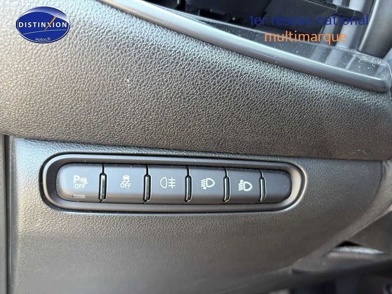 Boutons de commande des aides à la conduite sur tableau de bord noir de Fiat 500 électrique blanc, vue rapprochée côté gauche.