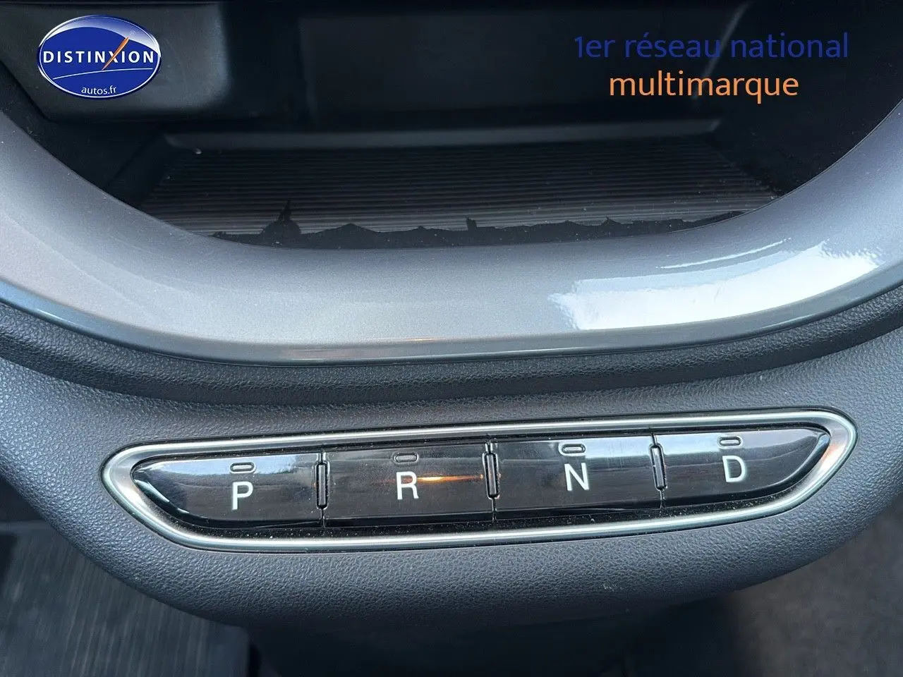 Gros plan sur la commande de boîte automatique en boutons de la Fiat 500 électrique blanche, version 2024.