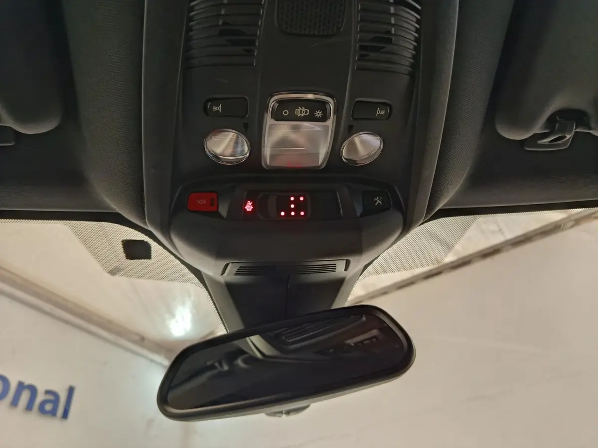 Vue intérieure du plafonnier et du rétroviseur central du Peugeot 5008 gris clair, avec commandes et voyants lumineux rouges.