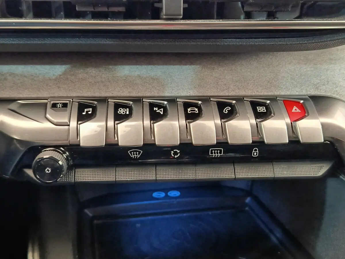 Gros plan sur la rangée de boutons métalliques et rouges du tableau de bord du Peugeot 5008 gris clair, version GT.