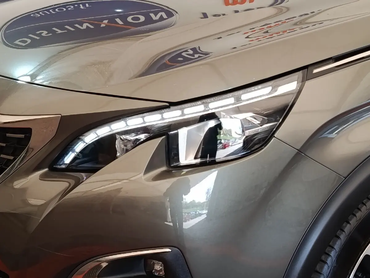 Gros plan sur le phare avant droit du Peugeot 5008 gris clair, mettant en valeur les LED distinctives et la carrosserie lisse.