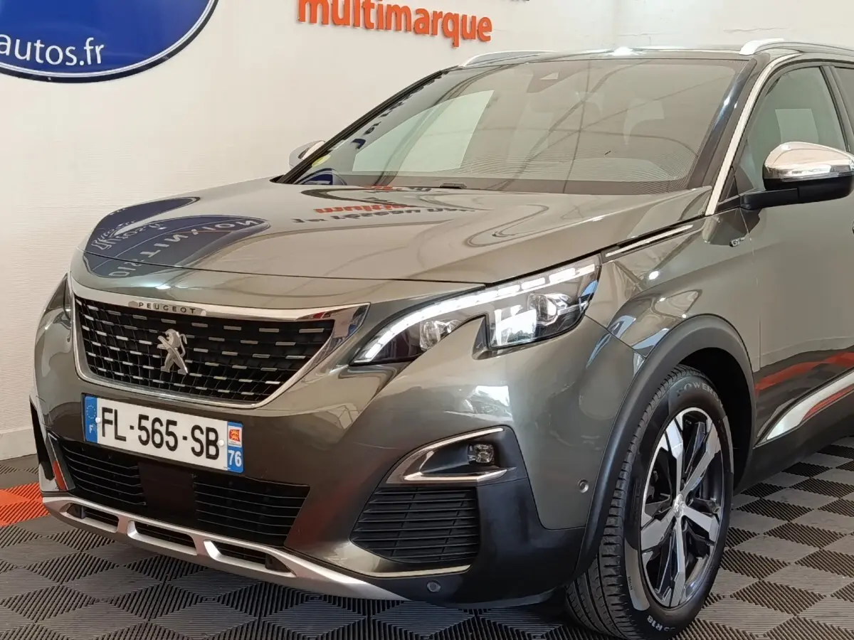 Peugeot 5008 gris clair en 3/4 avant droit, avec calandre chromée et phares LED distinctifs.