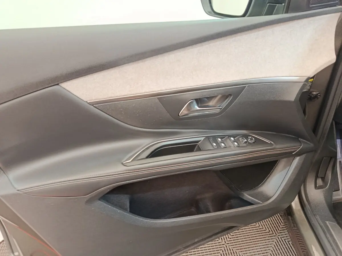 Vue rapprochée de la porte avant gauche du Peugeot 5008 gris clair, avec commandes électriques et garniture tissu et cuir.