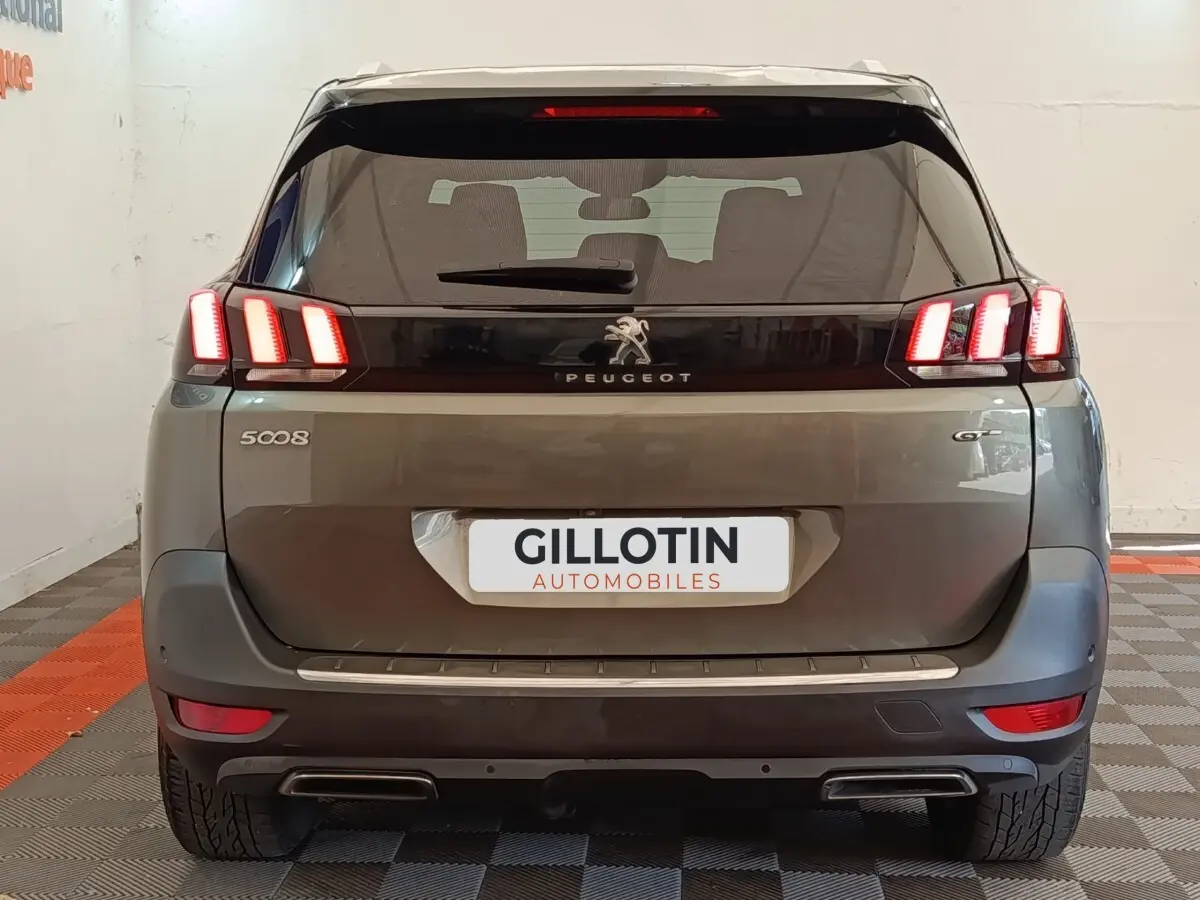 Vue arrière d'un Peugeot 5008 gris clair version GT avec feux LED distinctifs et double sortie d'échappement.