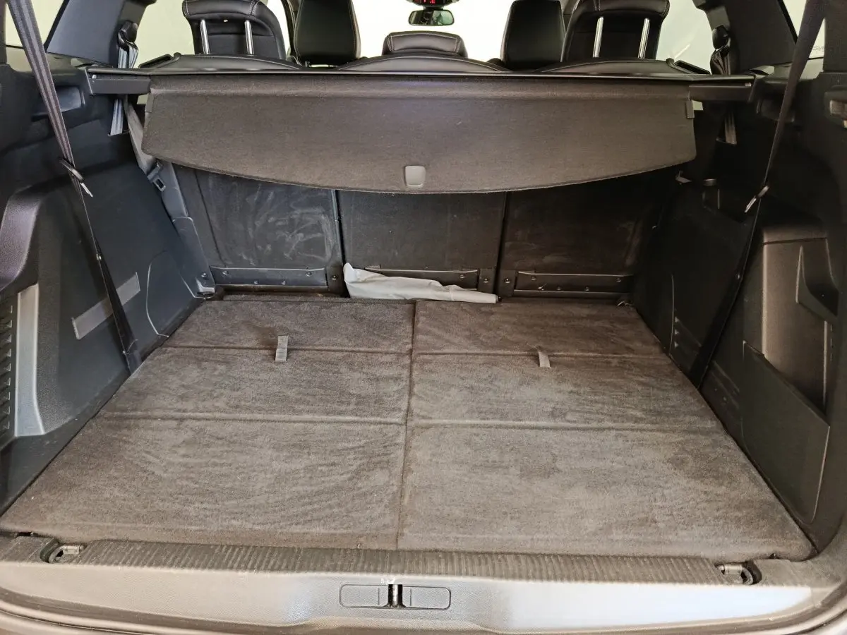 Vue du coffre arrière du Peugeot 5008 gris clair avec banquette rabattue et cache-bagages déployé.