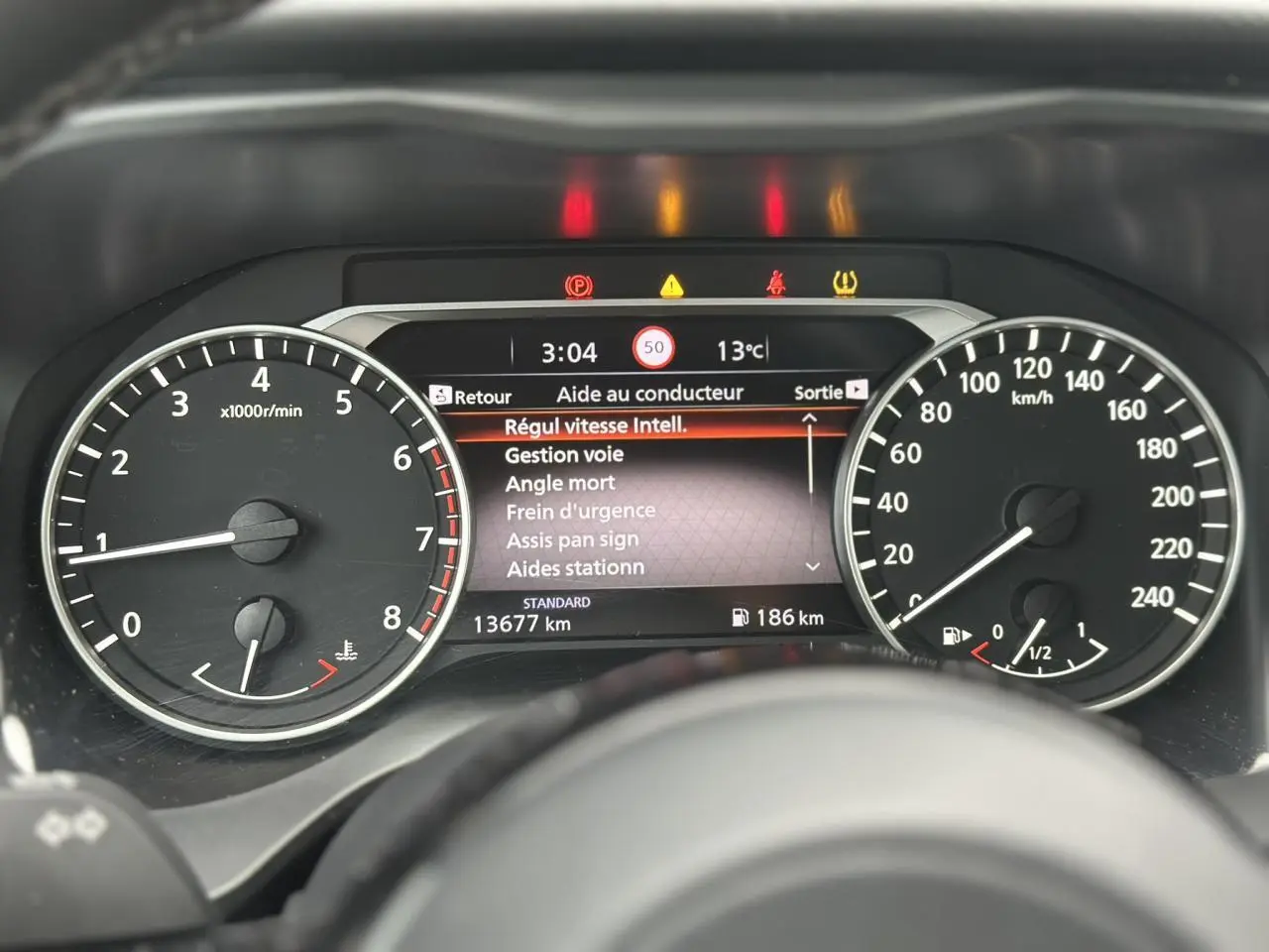 Vue rapprochée du tableau de bord du Nissan Qashqai 2025, affichant les compteurs et l'écran d'aide au conducteur.