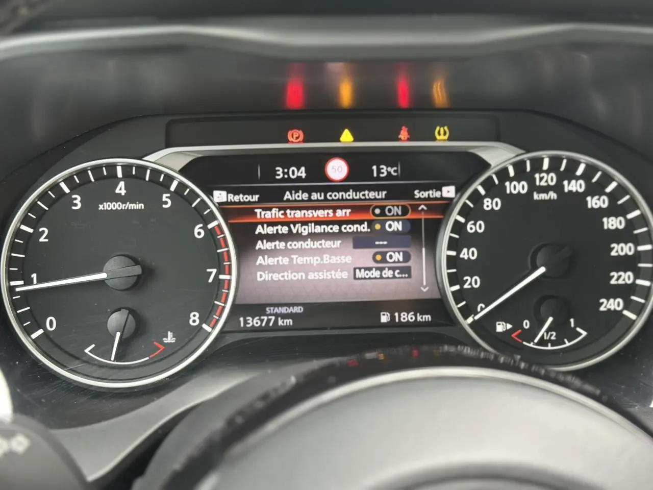 Tableau de bord du Nissan Qashqai 2025, affichage digital central avec alertes et compte-tours à gauche, vitesse à droite.