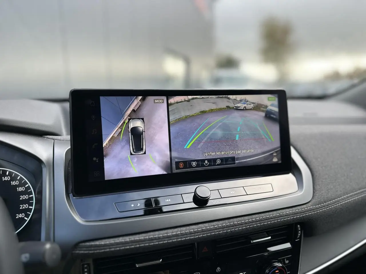 Vue intérieure du tableau de bord du Nissan Qashqai 2025, écran tactile affichant la caméra de recul et vue à 360° en noir nacré.