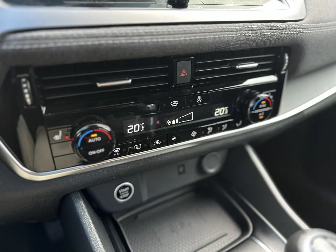 Gros plan sur la console centrale du Nissan Qashqai 2025, affichant la climatisation automatique bi-zone et le bouton Start/Stop.