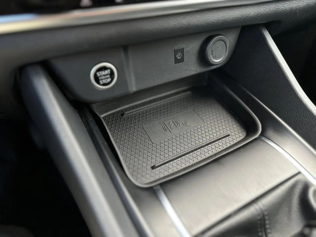 Gros plan sur la console centrale du Nissan Qashqai 2025 avec zone de recharge sans fil et bouton Start/Stop.