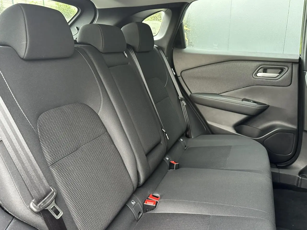 Vue latérale droite de la banquette arrière noire du Nissan Qashqai 2025, avec ceintures et garnitures de porte visibles.