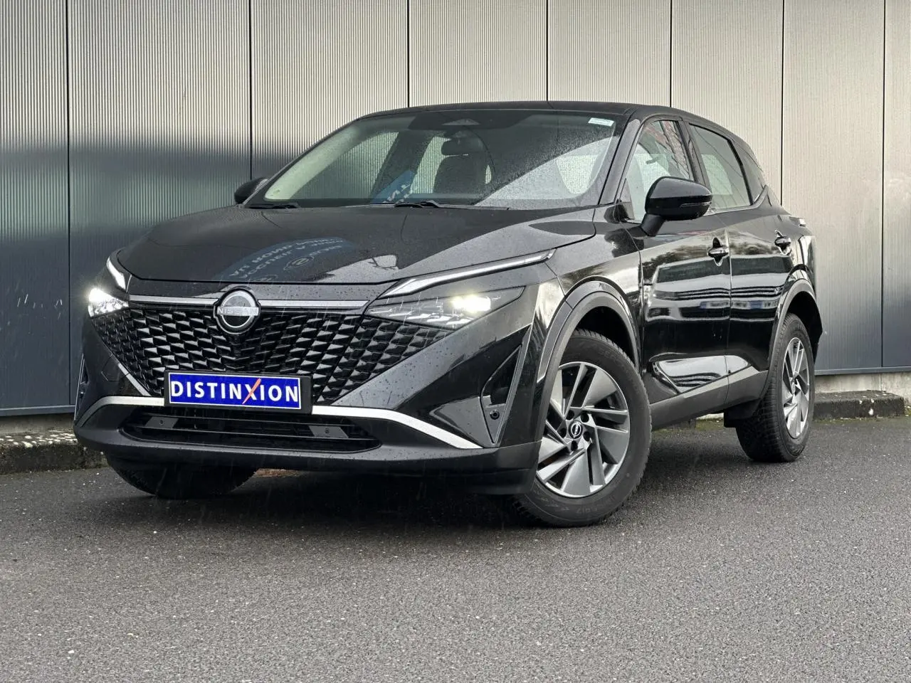 Nissan Qashqai noir nacré en 3/4 avant droit, avec calandre distinctive et feux LED allumés.