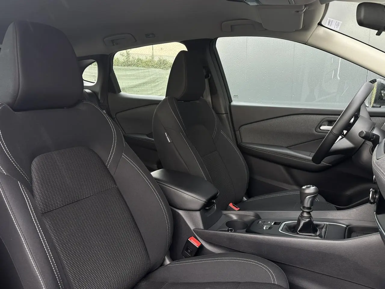 Vue intérieure côté droit du Nissan Qashqai 2025 noir nacré, sièges et console centrale avec boîte manuelle.