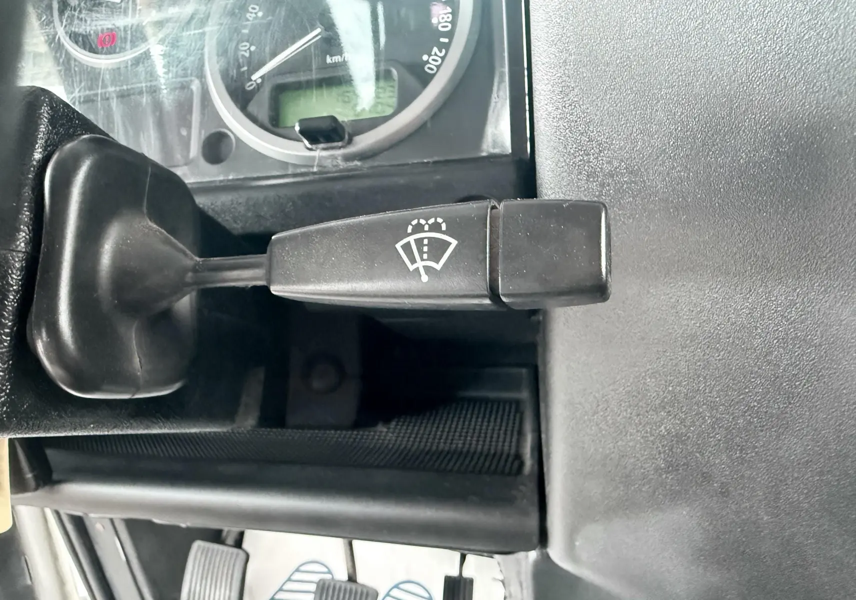 Gros plan sur le levier de commande d’essuie-glace noir dans l’habitacle gris foncé du Land Rover Defender blanc de 2007.