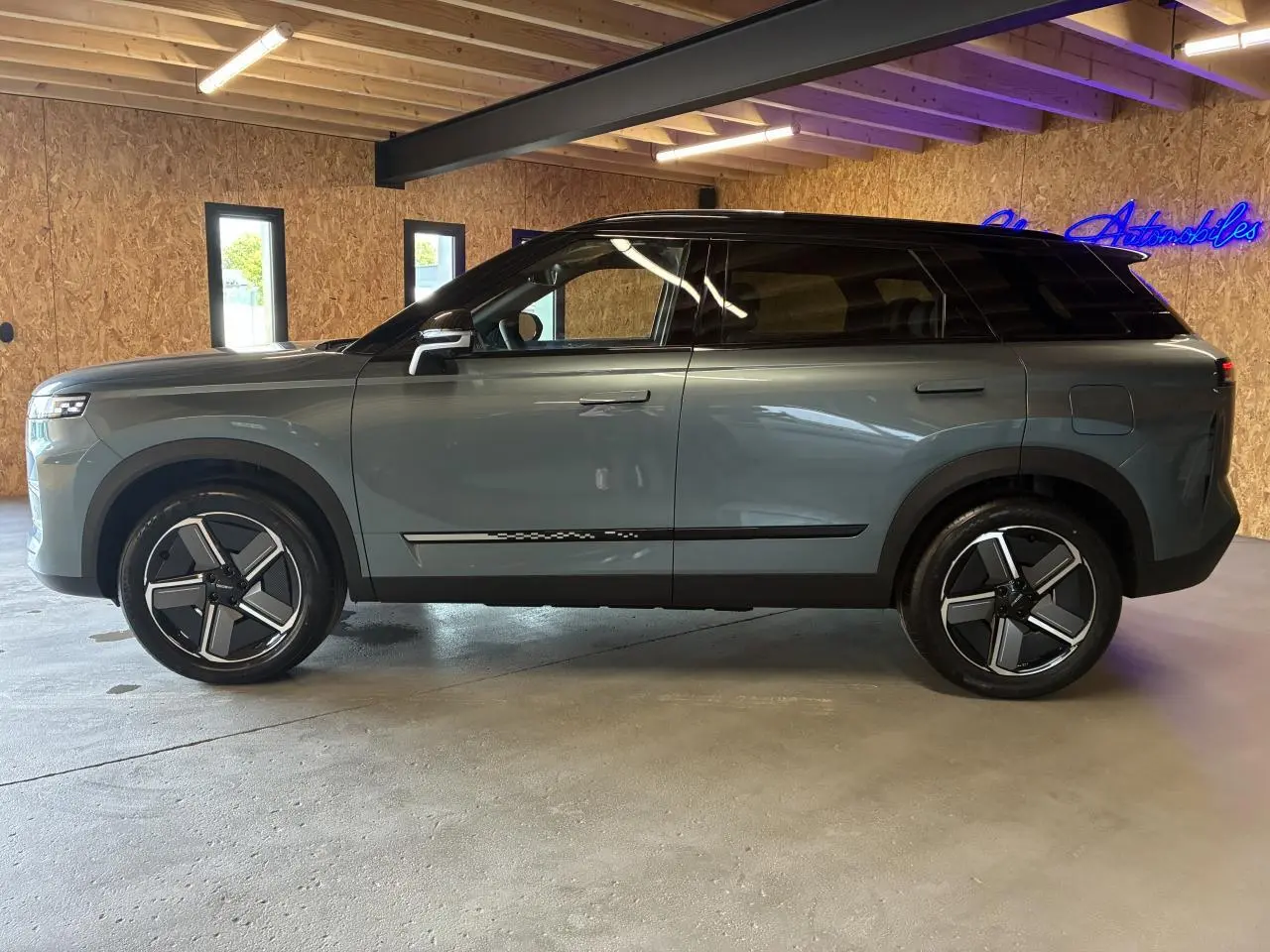 SUV JAECOO J7 gris olive avec toit noir vu de profil côté gauche, jantes alliage 19 pouces et vitres teintées.