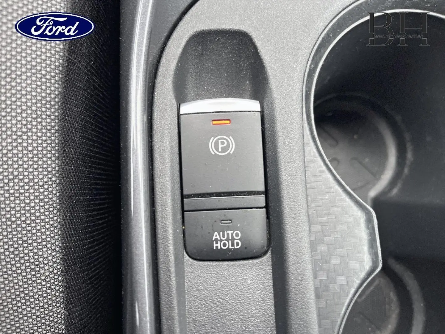 Gros plan sur la commande de frein à main électrique et fonction Auto Hold dans un intérieur noir texturé.