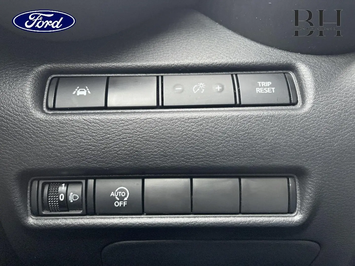 Panneau de commandes intérieures en plastique noir avec boutons de réglage d’éclairage et fonctions d’assistance, sans lien visible avec Nissan Juke.