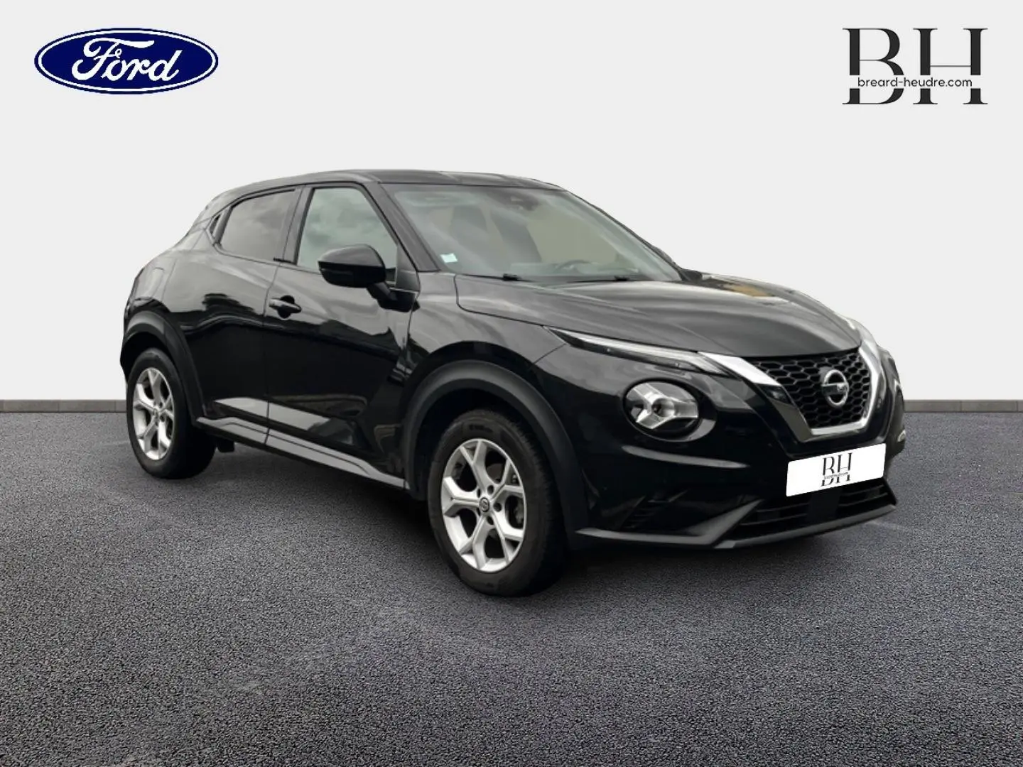 Nissan Juke noir métallisé en 3/4 avant droit, avec jantes alu et calandre distinctive V-Motion.