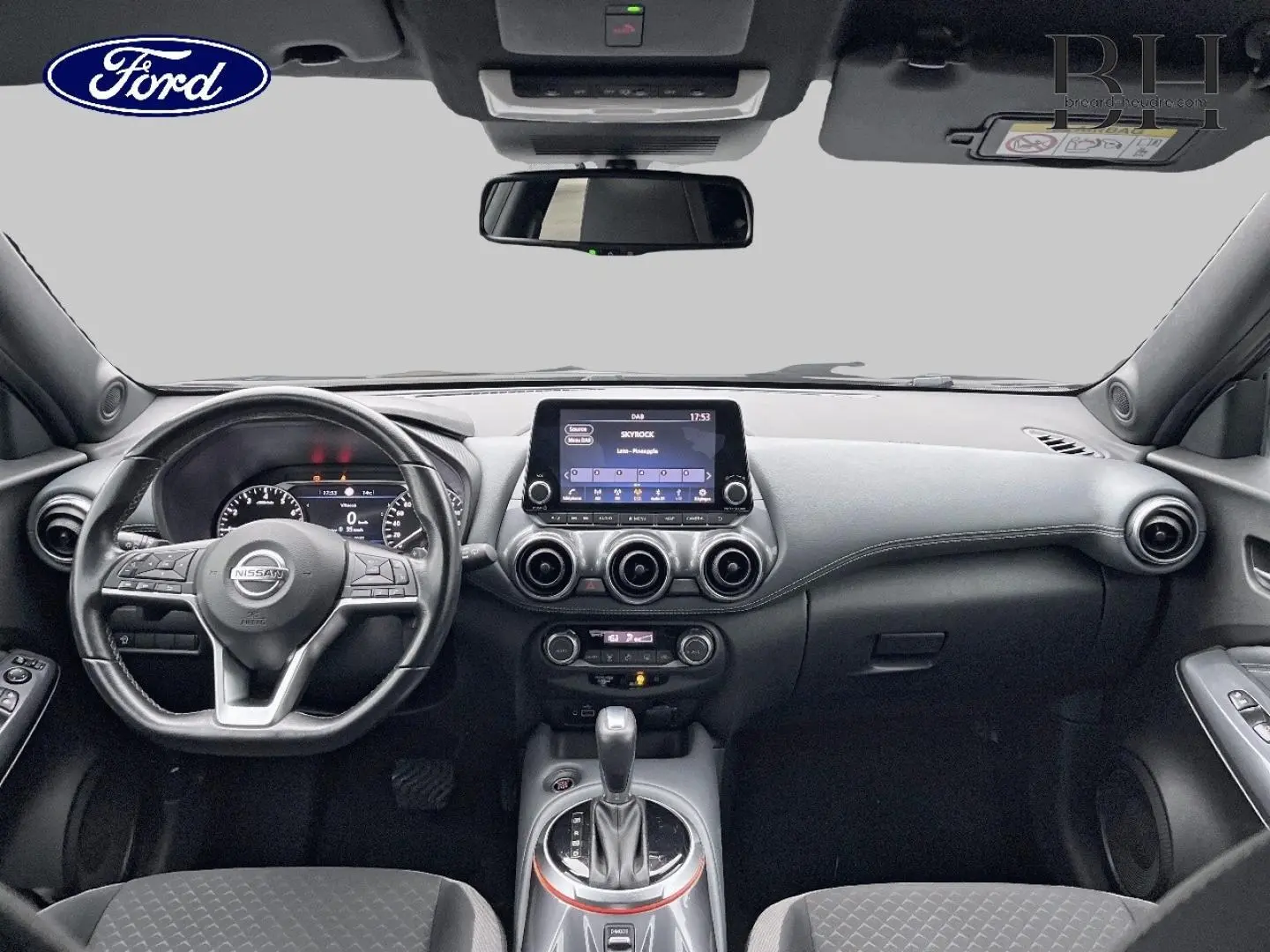 Vue intérieure avant du Nissan Juke noir métallisé 2020, avec tableau de bord moderne et écran tactile central.
