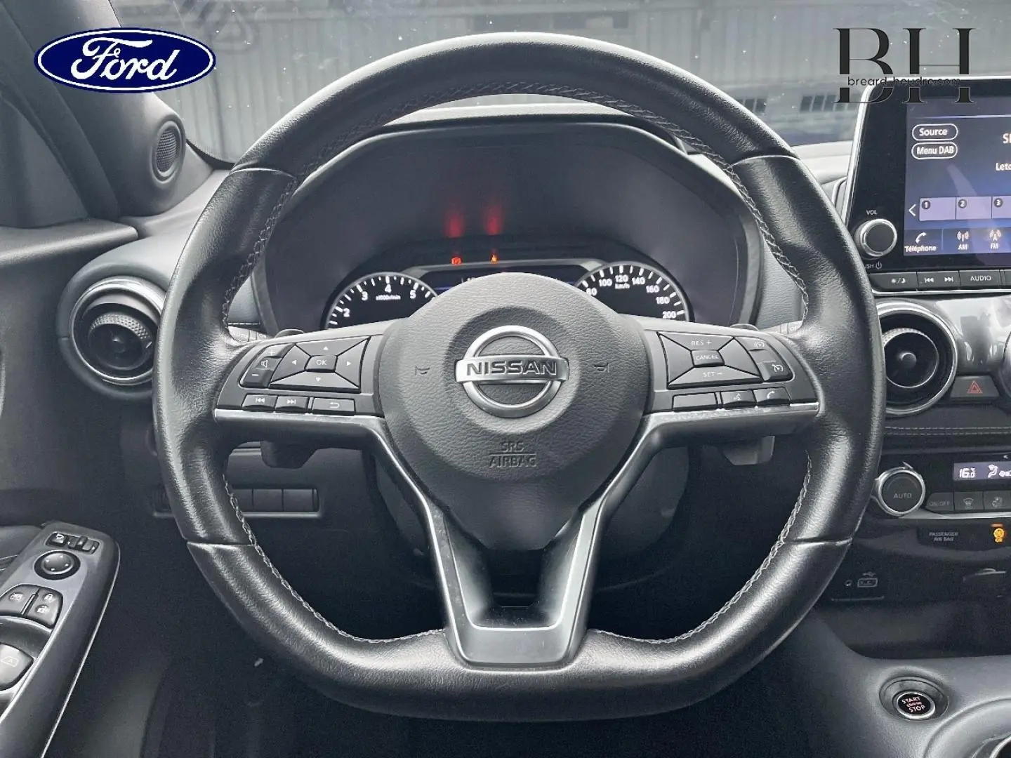 Vue rapprochée du volant cuir noir du Nissan Juke 2020 avec commandes multifonctions et tableau de bord en arrière-plan.