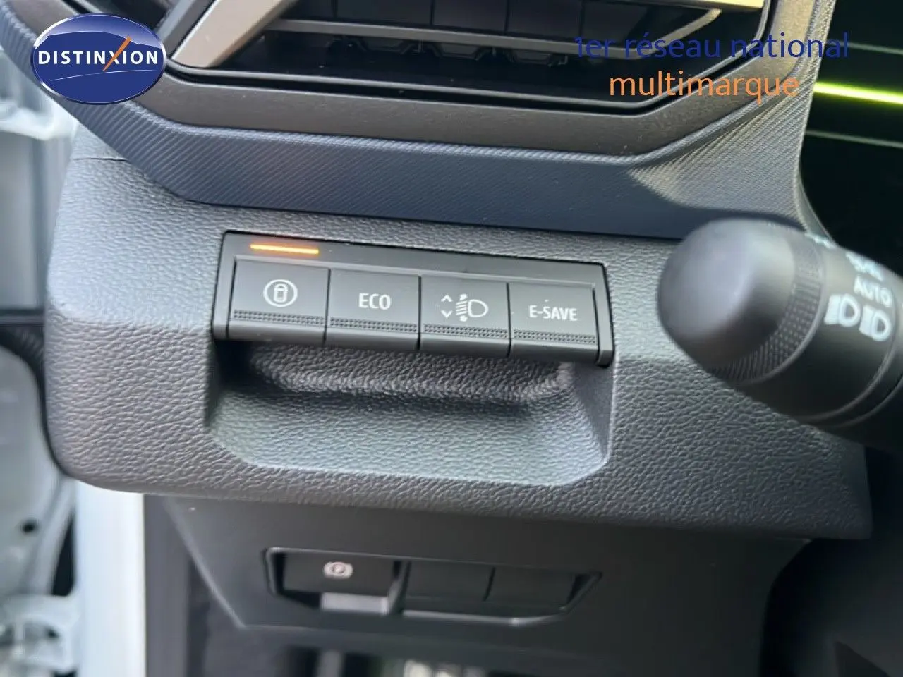 Gros plan sur les commandes ECO et E-SAVE du tableau de bord du Dacia Duster blanc glacier 2025, côté gauche.