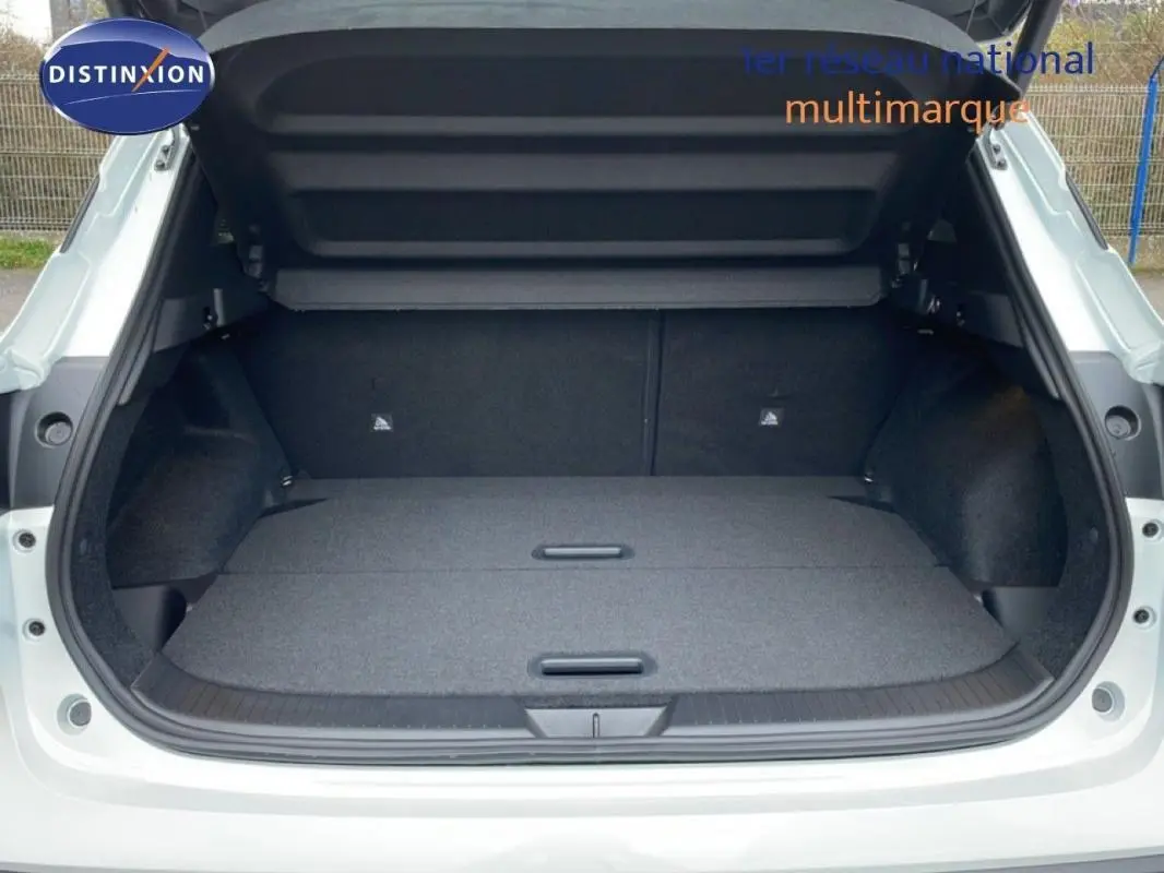 Coffre ouvert vu de l'arrière d'un Nissan Qashqai blanc 2025, montrant un espace de chargement plat et spacieux.