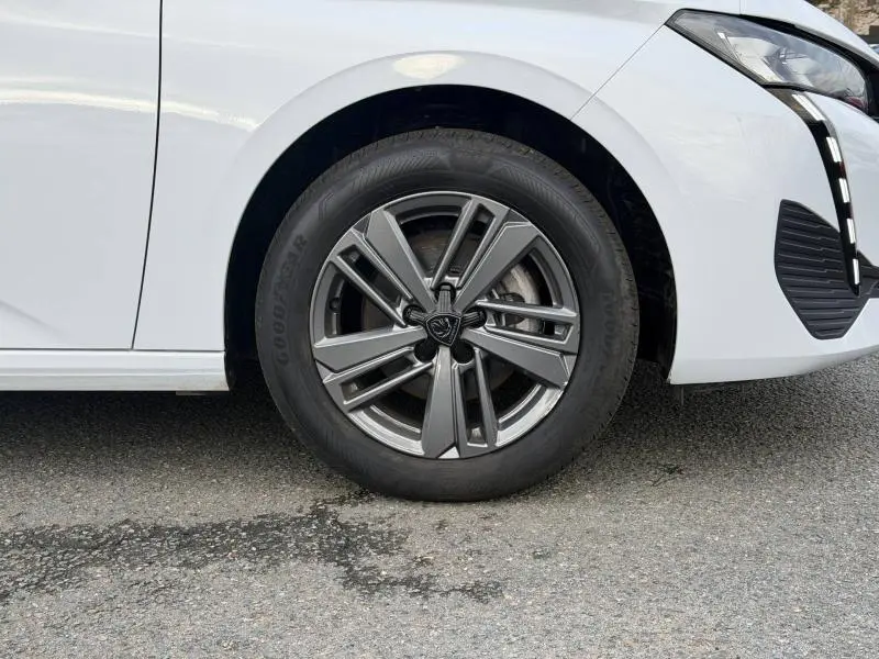 Gros plan sur la roue avant droite de la Peugeot 308 2024 blanc Okénite avec jante alliage au design moderne.