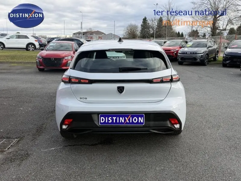 Vue arrière d'une Peugeot 308 blanche Okénite 2024, avec feux arrière LED et logo noir au centre du hayon.