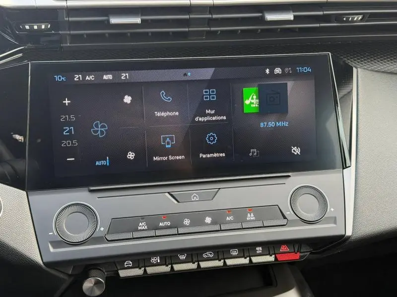 Vue rapprochée de l’écran tactile et des commandes climatisation de la Peugeot 308 2024 en blanc Okénite.