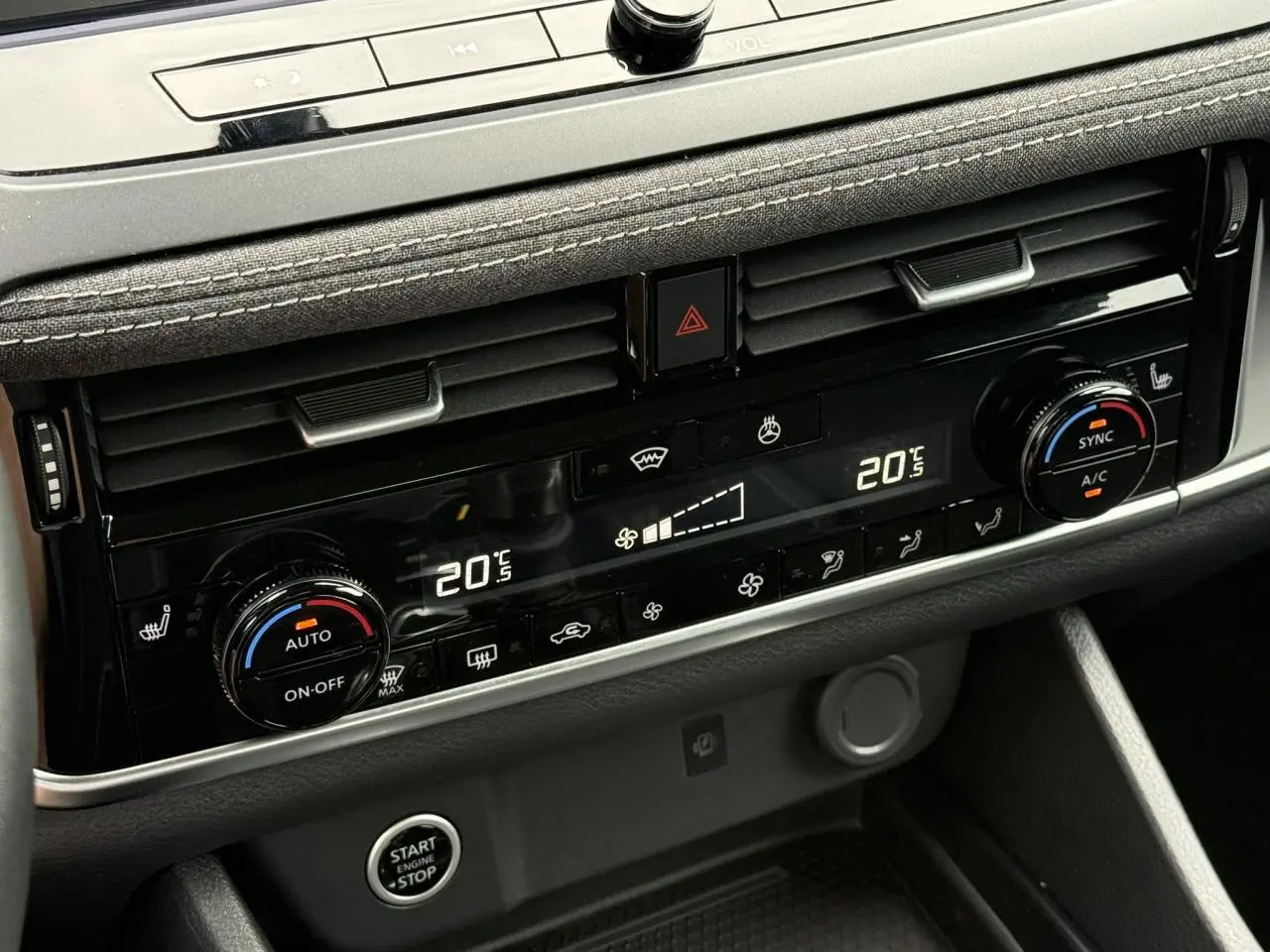 Gros plan sur la console centrale du Nissan Qashqai 2025, affichage digital de la climatisation bi-zone et commandes rotatives.