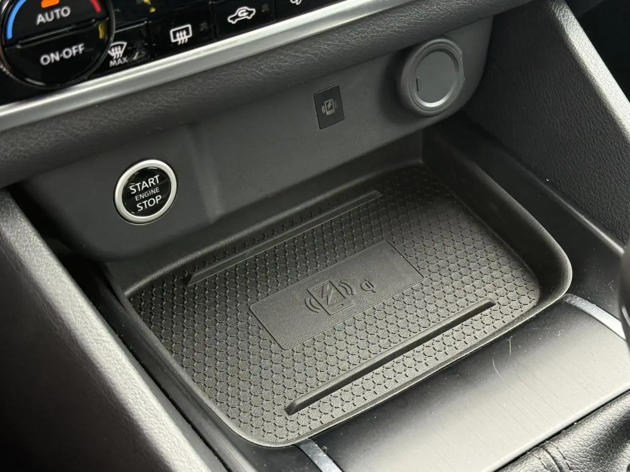 Gros plan sur la console centrale du Nissan Qashqai 2025 bleu Magnétique, montrant le chargeur à induction et le bouton Start/Stop.