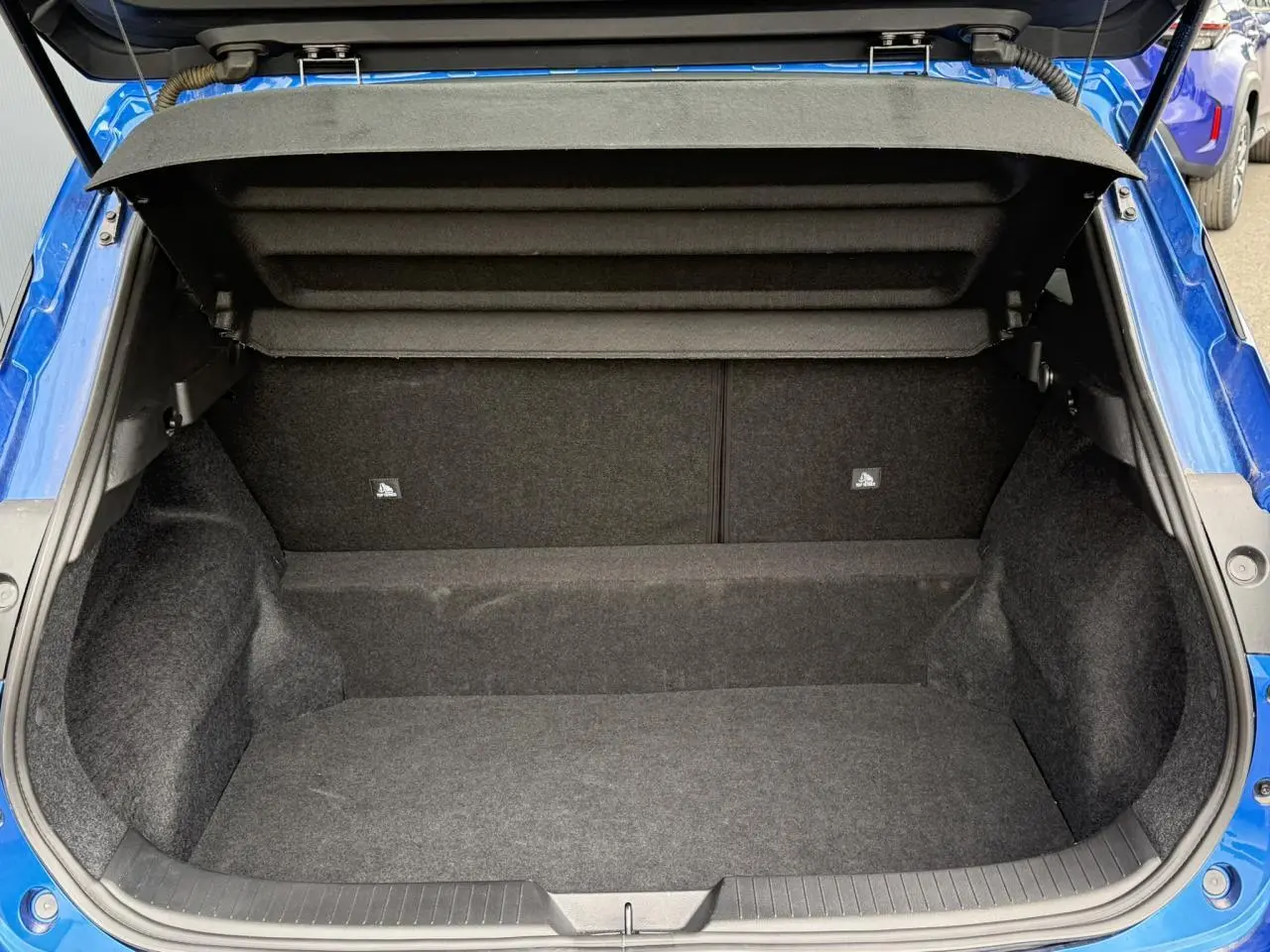 Coffre ouvert vu de l'arrière du Nissan Qashqai bleu magnétique, montrant l'espace de chargement vide et la moquette intérieure.