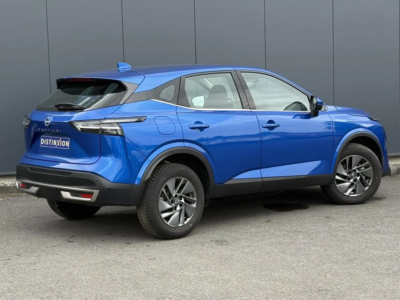 Vue 3/4 arrière droite d'un Nissan Qashqai 2025 bleu magnétique avec jantes alliage et feux LED distinctifs.