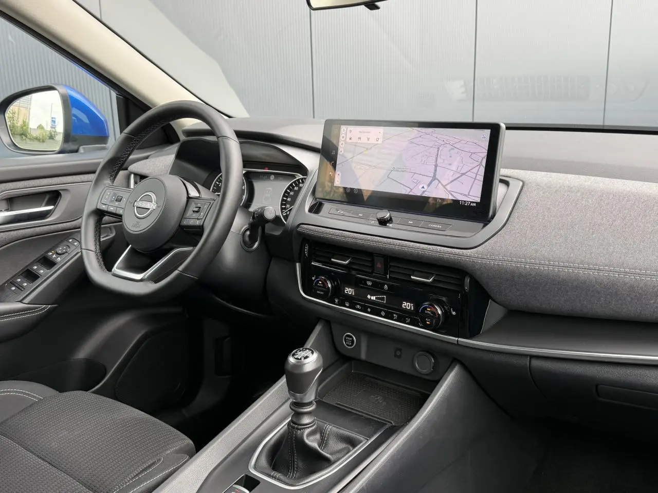 Vue intérieure côté conducteur du Nissan Qashqai 2025 bleu magnétique, avec tableau de bord moderne et écran tactile central.