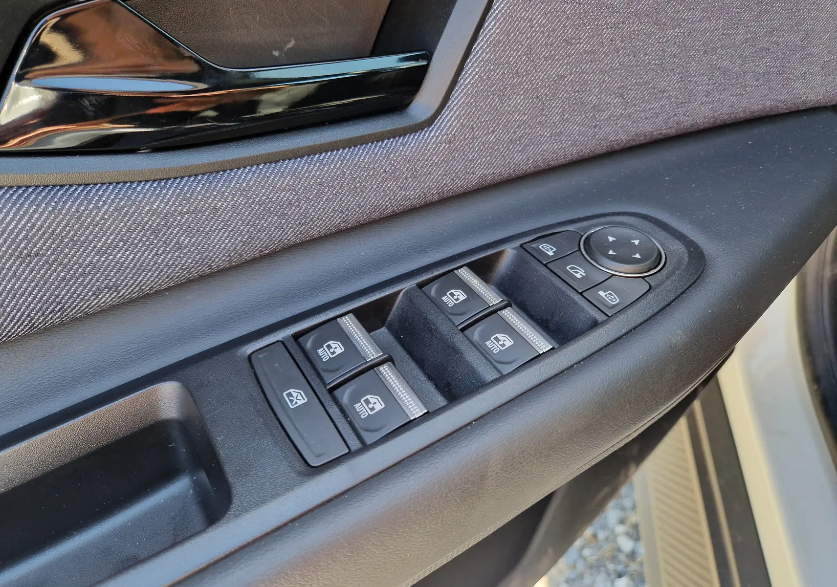 Gros plan sur la commande des vitres et rétroviseurs côté gauche de la porte d’une Renault R5 E-TECH blanc nacré/noir.