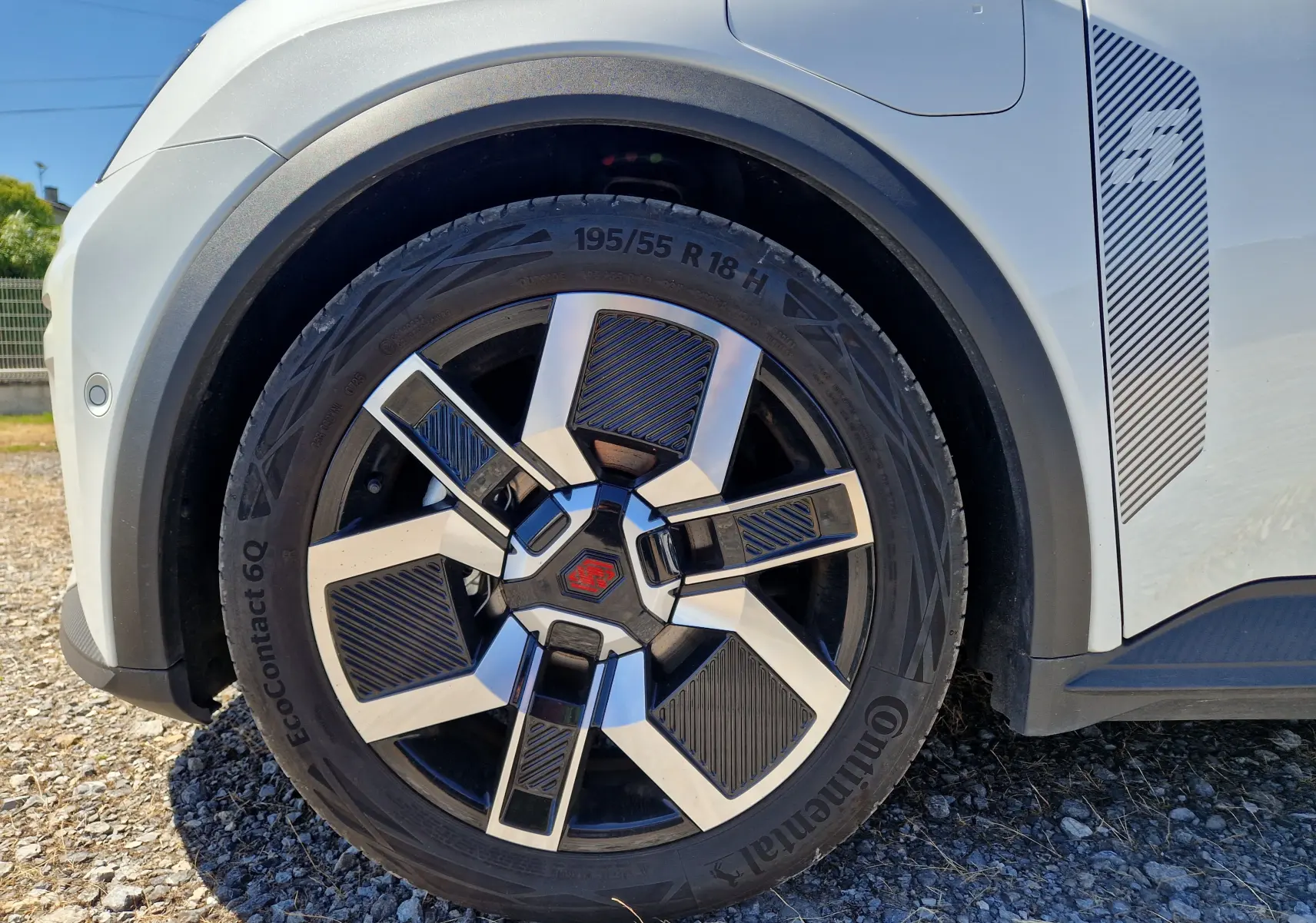 Gros plan sur la roue avant gauche de la Renault R5 E-TECH blanche nacrée avec jante noire et argentée au design moderne.