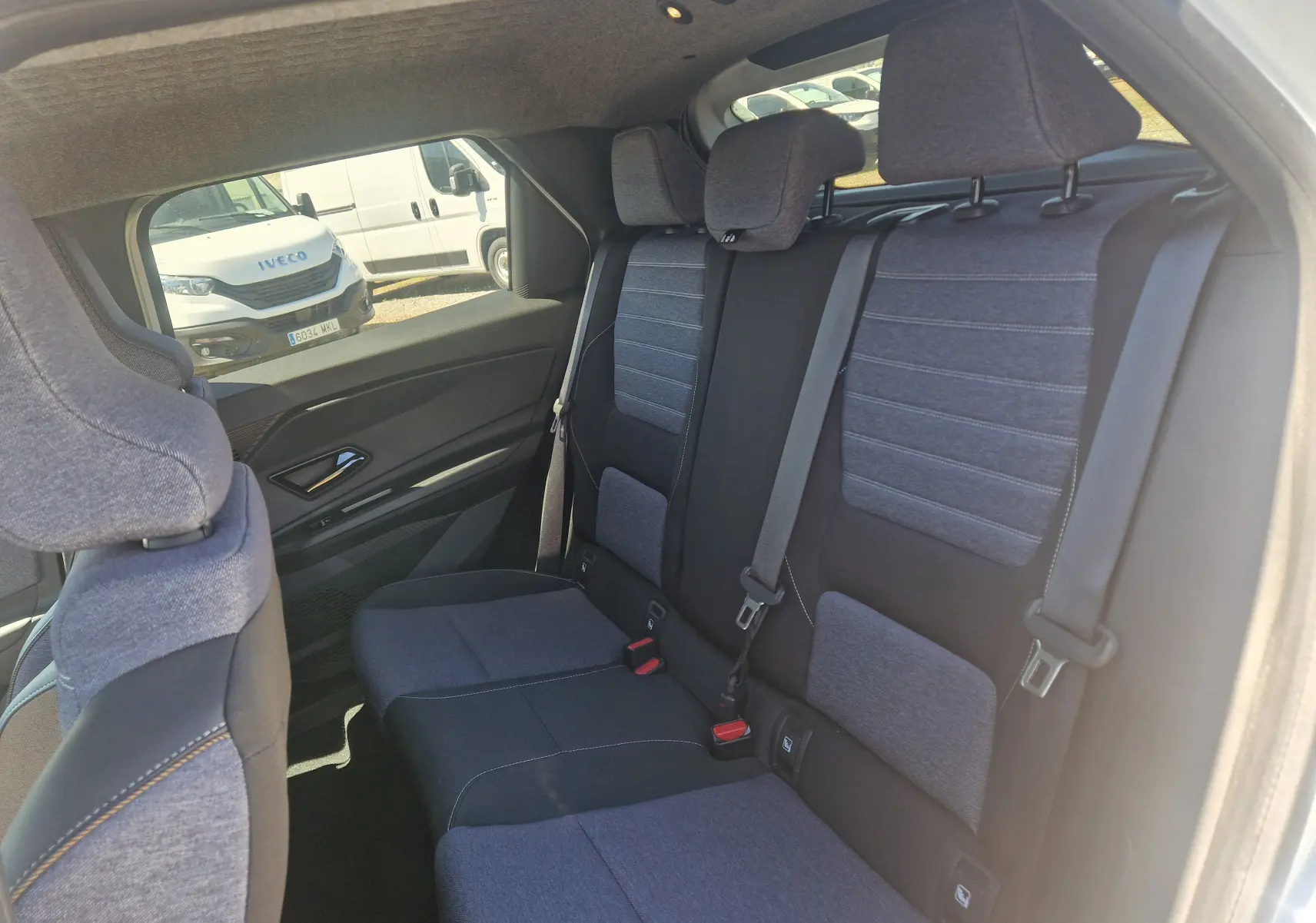 Vue intérieure arrière droite des sièges tissu bleu et noir du Renault R5 E-TECH 2025, avec appuie-têtes et ceintures visibles.