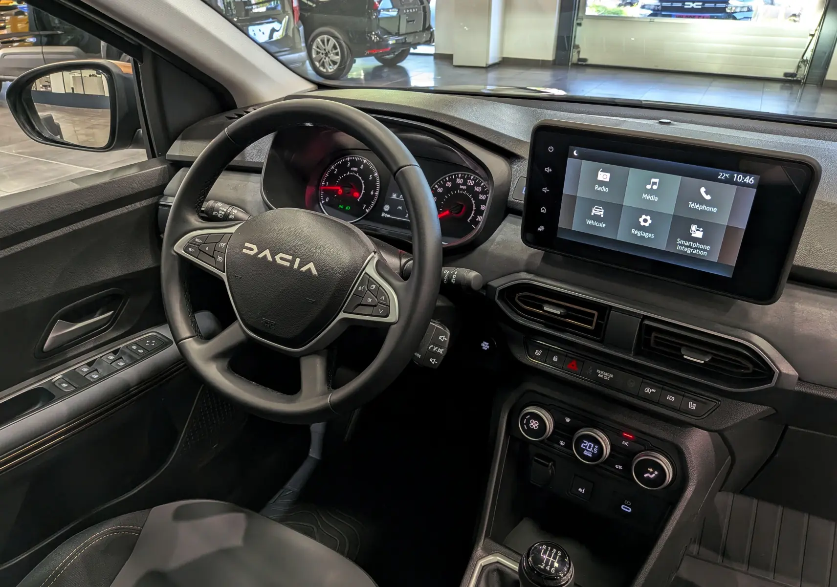 Vue intérieure côté conducteur du tableau de bord et volant du Dacia Sandero Stepway 2025 avec écran tactile et levier de vitesses manuel.